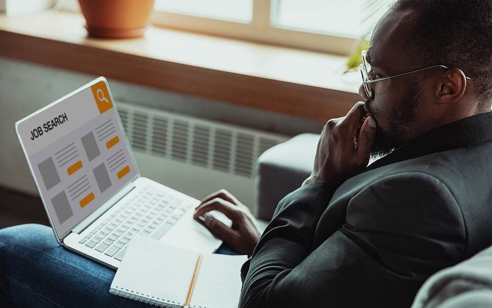 Man on laptop looks for a job while writing his resume