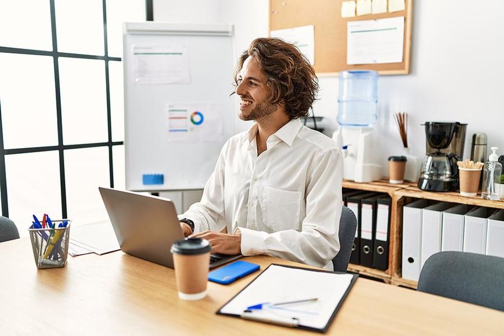 Man on laptop smiles at work