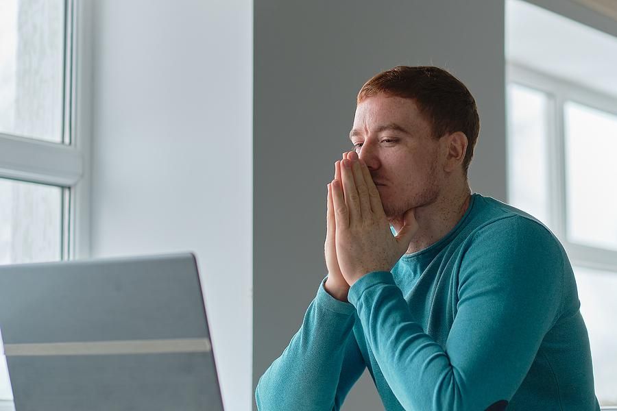 Man on laptop struggles to write his resume after getting fired