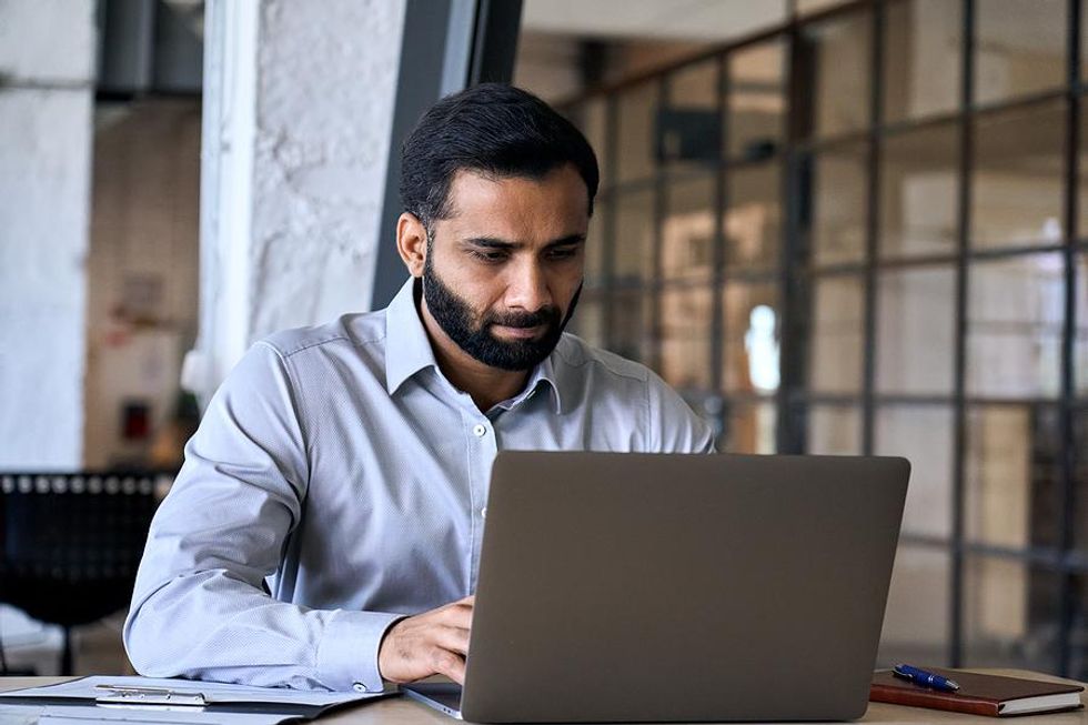 Man on laptop uses marketing tools and strategies to navigate compliance