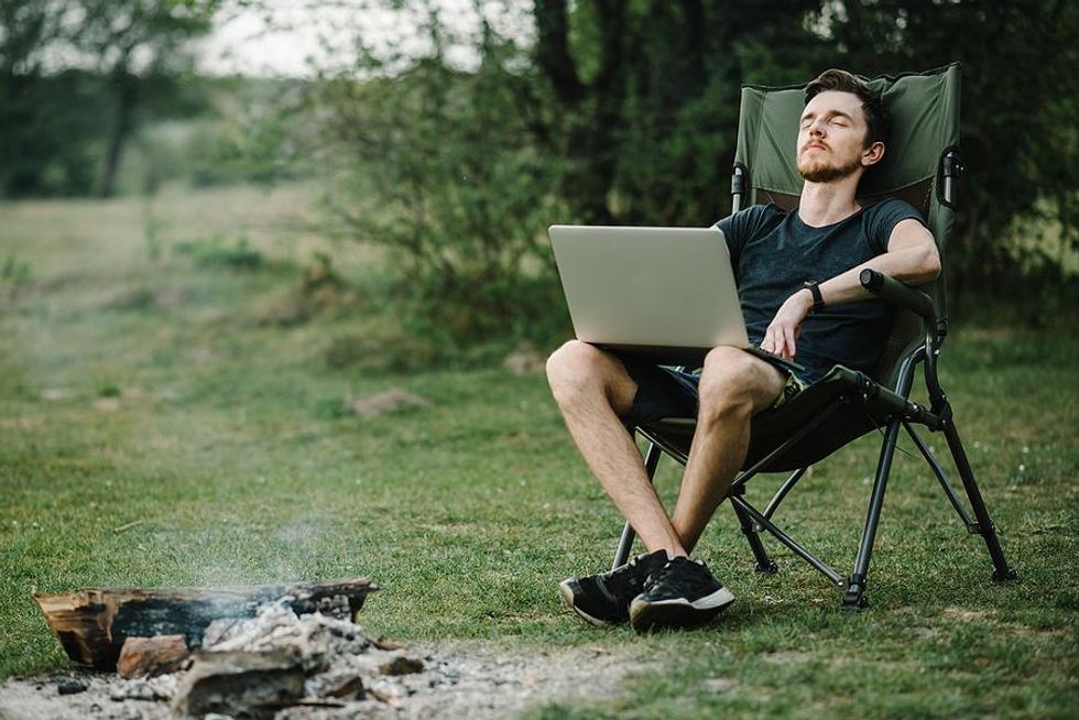 Man on laptop works while camping in the summer