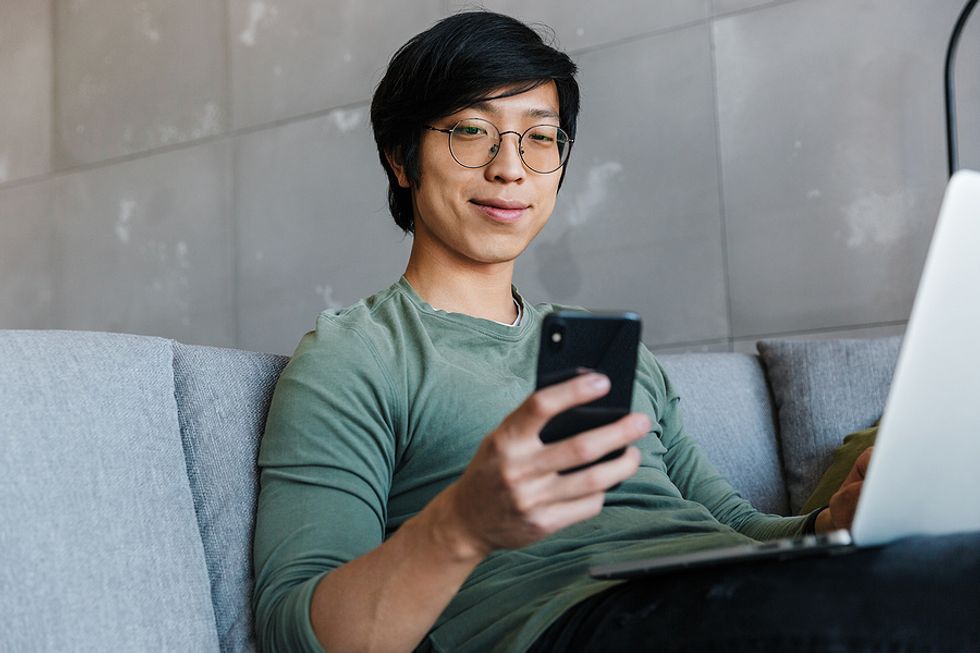 Man on phone and laptop connects with someone on LinkedIn