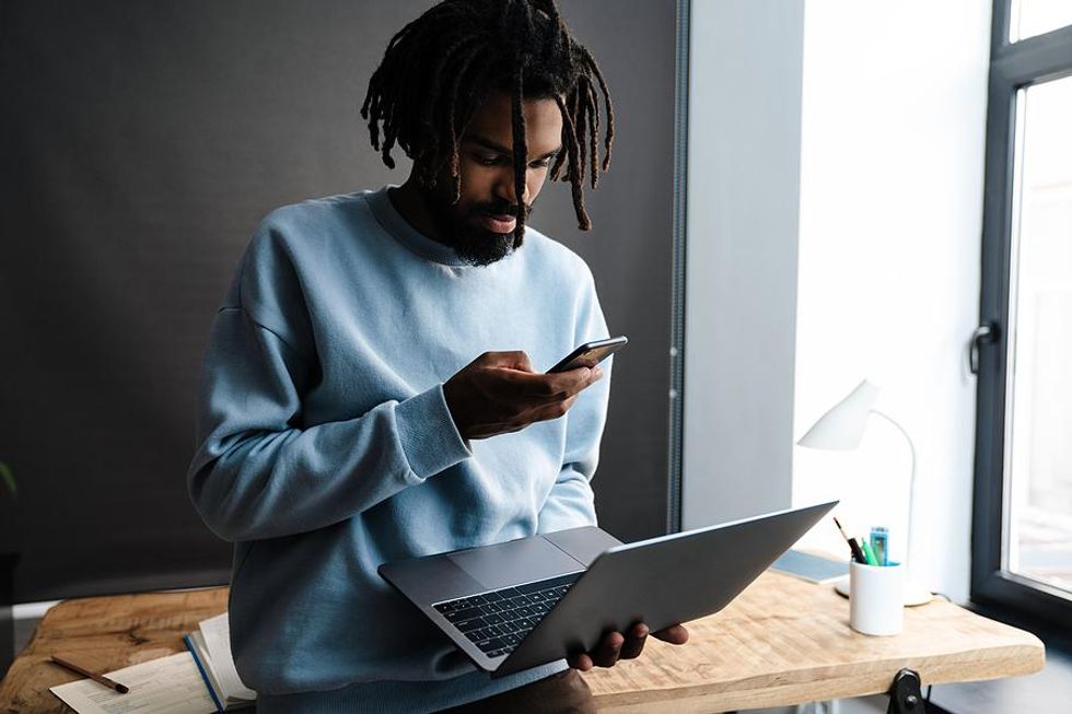 Man on phone and laptop optimizes his LinkedIn profile