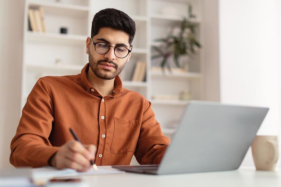 Man prepares for a job interview by writing down his answers to interview questions