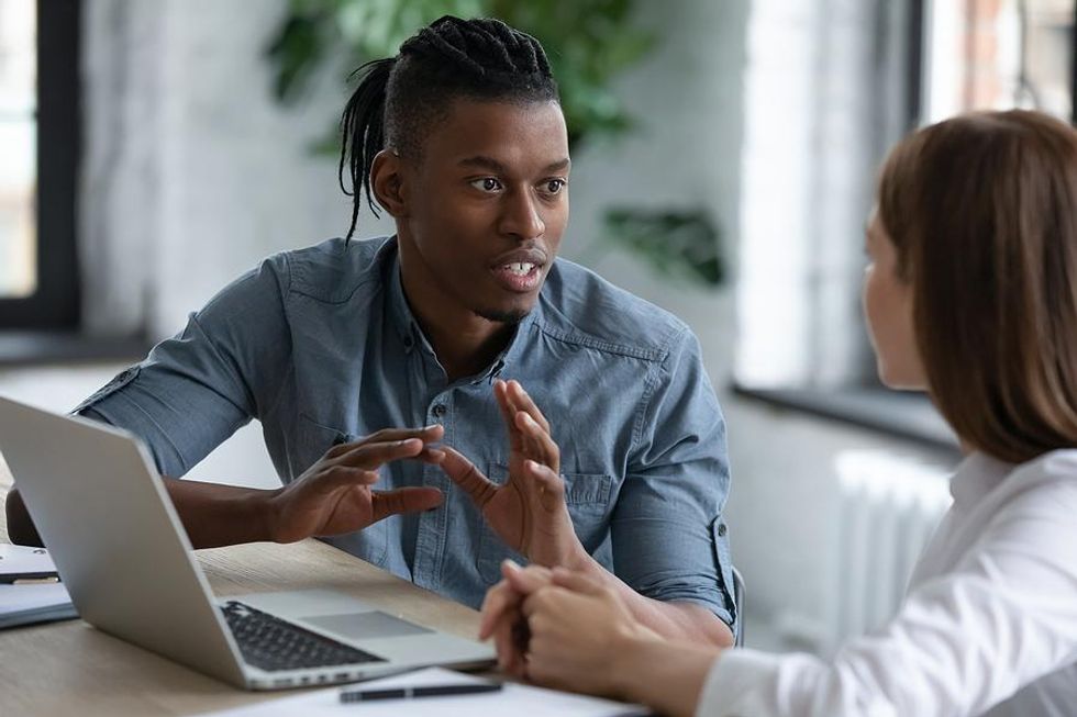Man seeks professional development at work while talking to a coworker