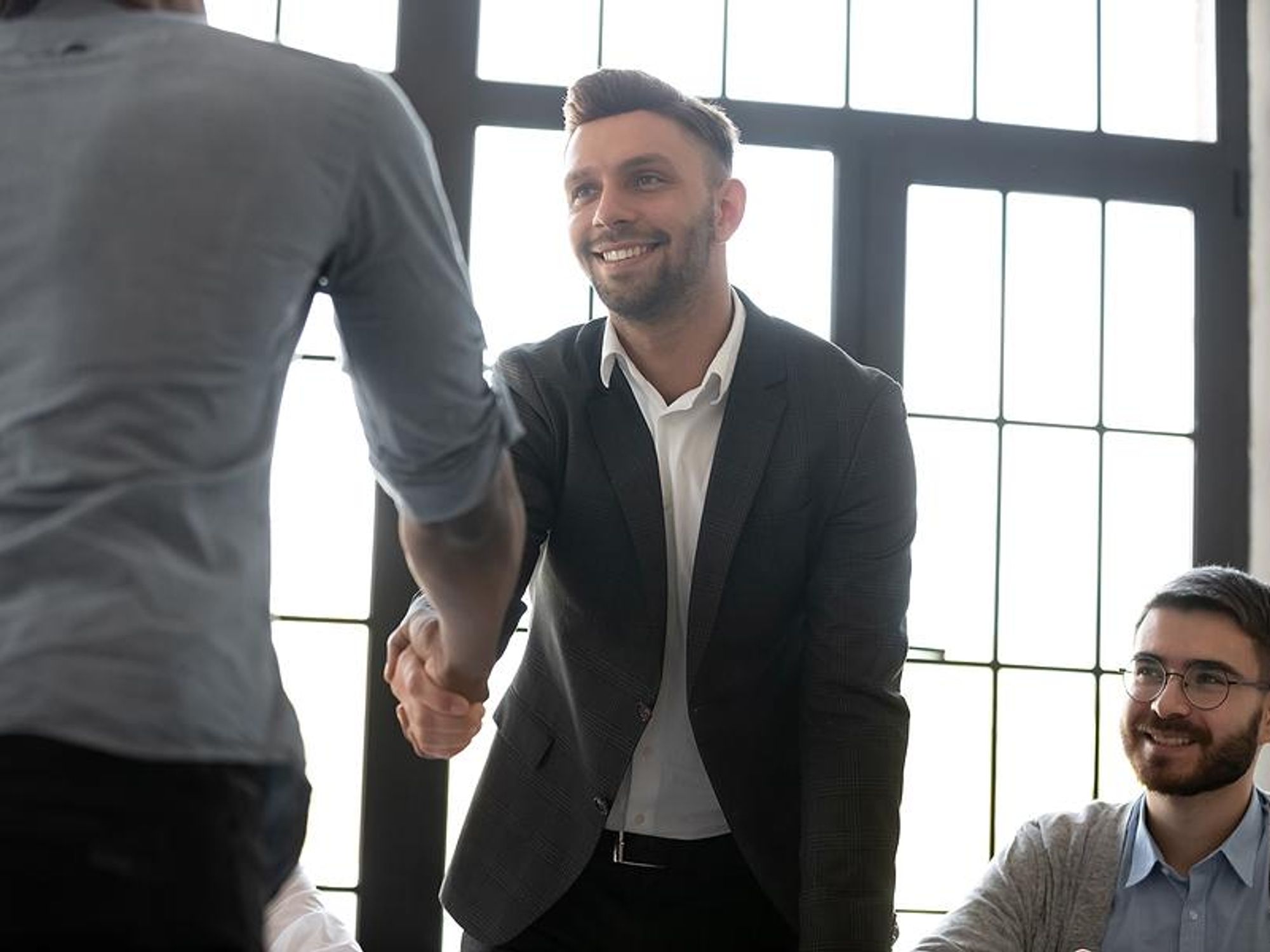 Man shakes hands after successfully getting his foot in the door at a company