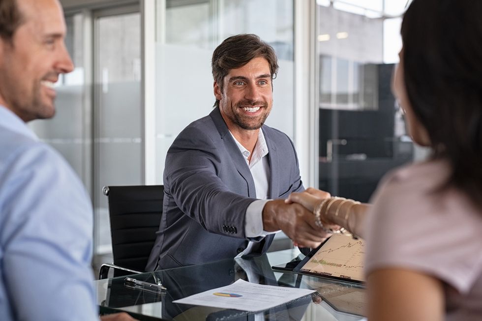 Man shakes hands with a woman during a work meeting