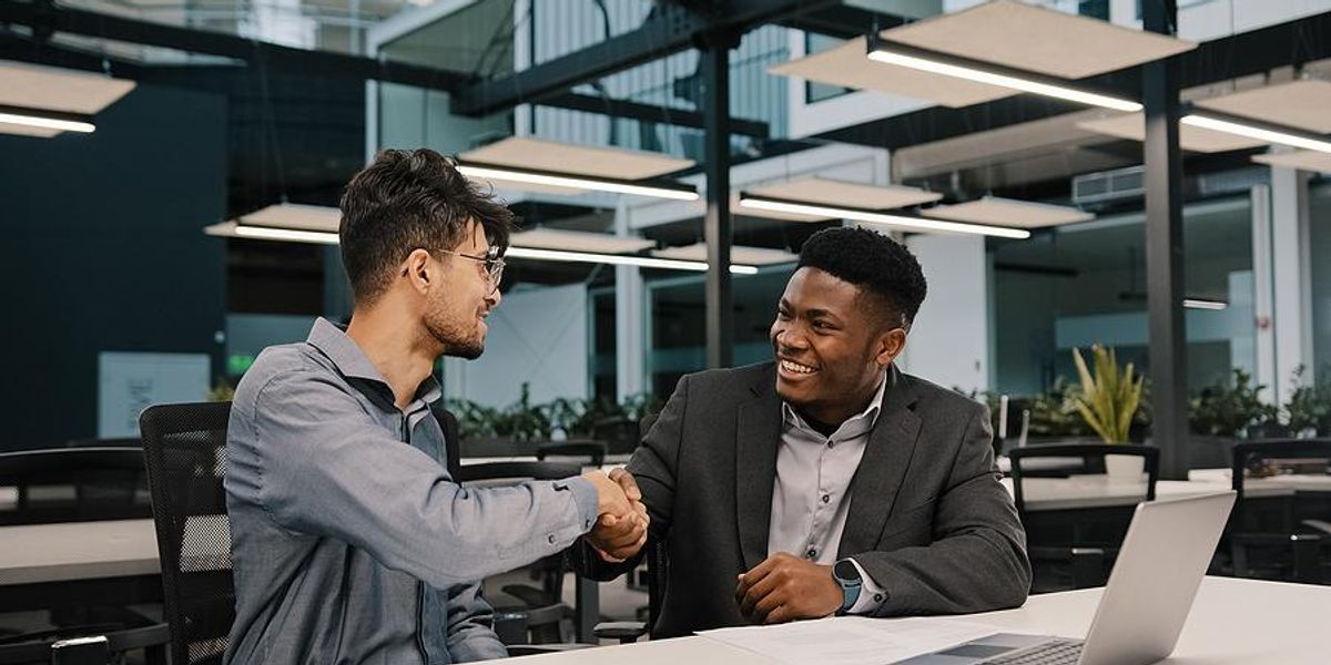 man shakes hands with his boss after he gives him a raise