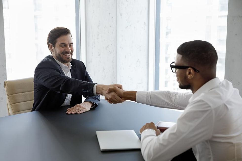 Seorang pria berjabat tangan dengan manajer perekrutan setelah wawancara kerja