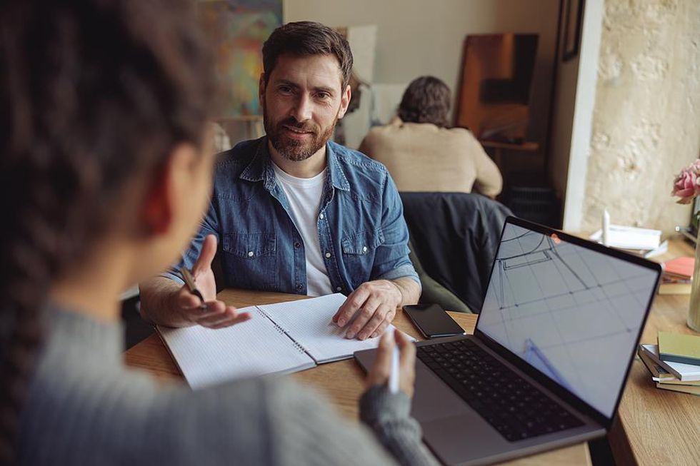 Man takes notes during a meeting with a colleague