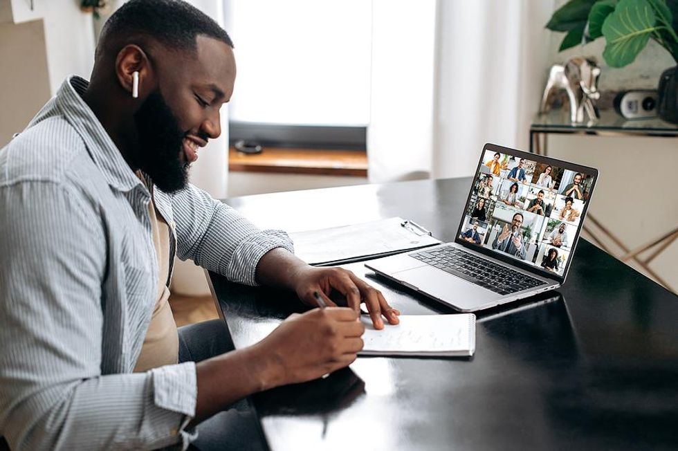 Man takes notes during a virtual work meeting