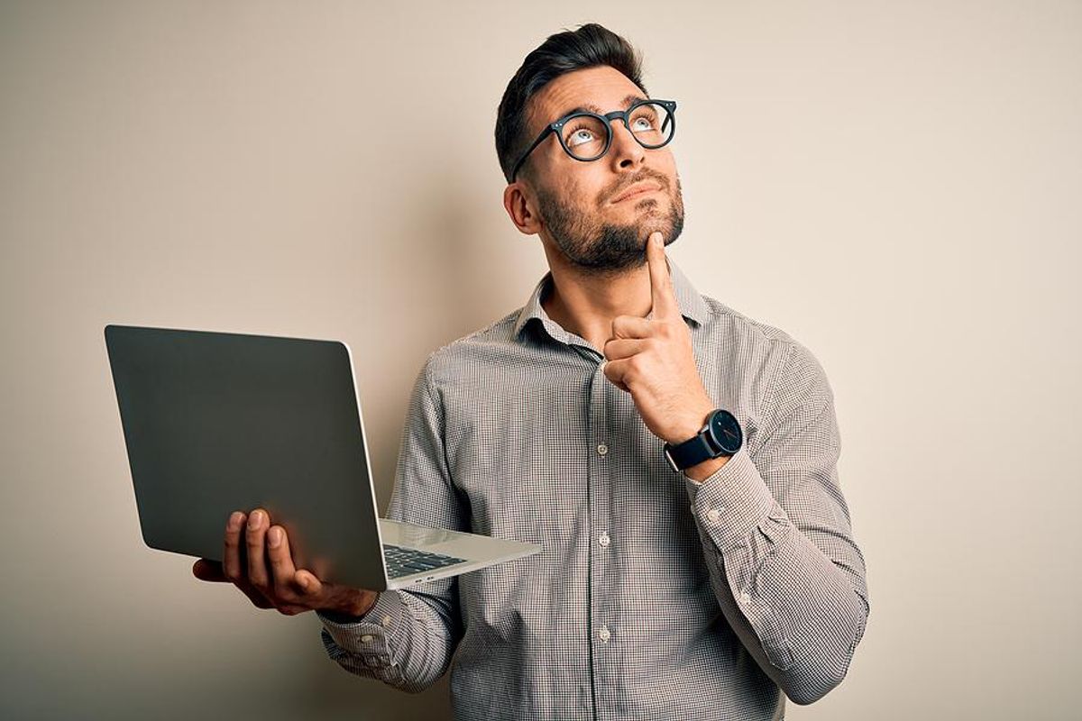 Man thinks about his desired salary while holding his laptop