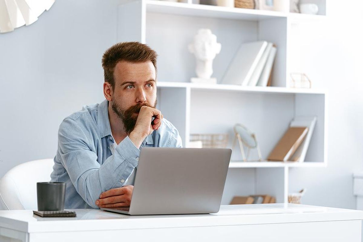 Man thinks about how to write a disruptive cover letter on his laptop