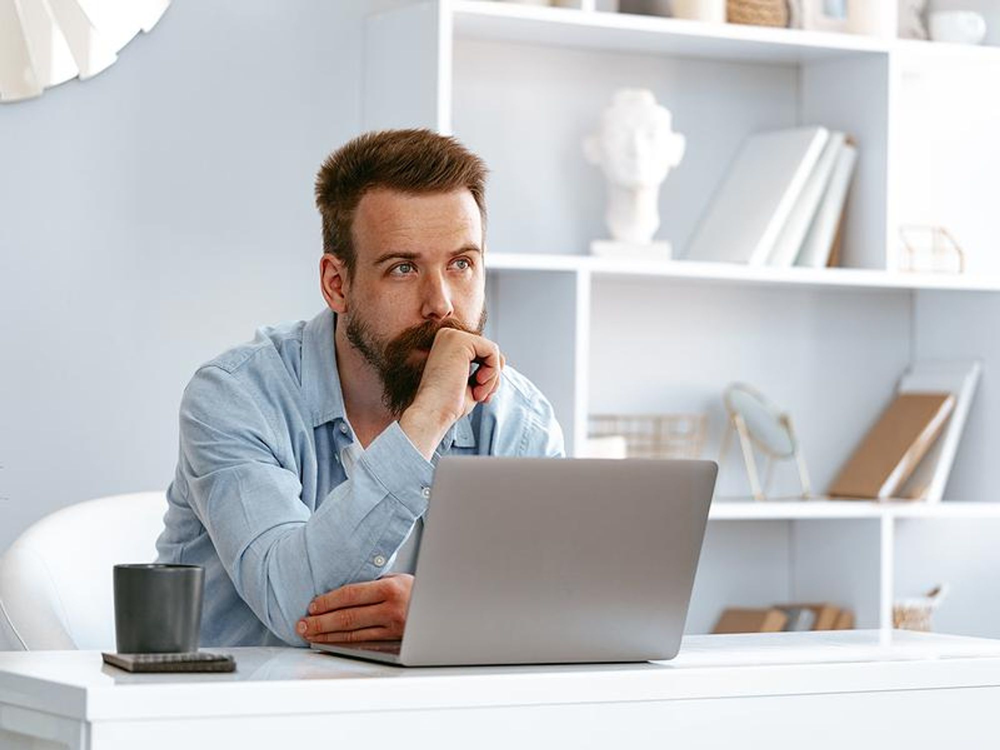 Man thinks about how to write a disruptive cover letter on his laptop