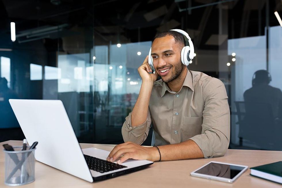 Man wearing headphones takes online career courses on his laptop at work