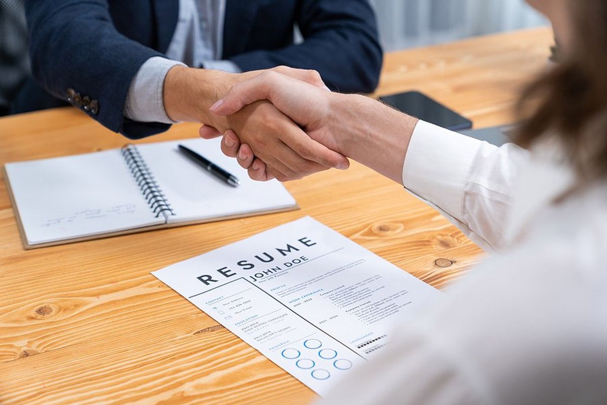 Man with resume shakes hands with the hiring manager before a job interview