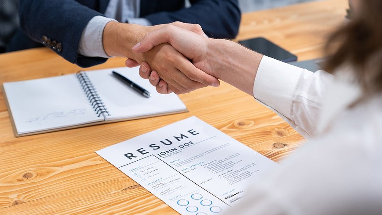 Man with resume shakes hands with the hiring manager before a job interview