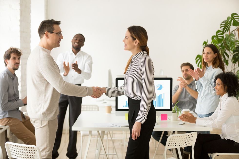 Manager congratulating a team member by shaking their hand at the office