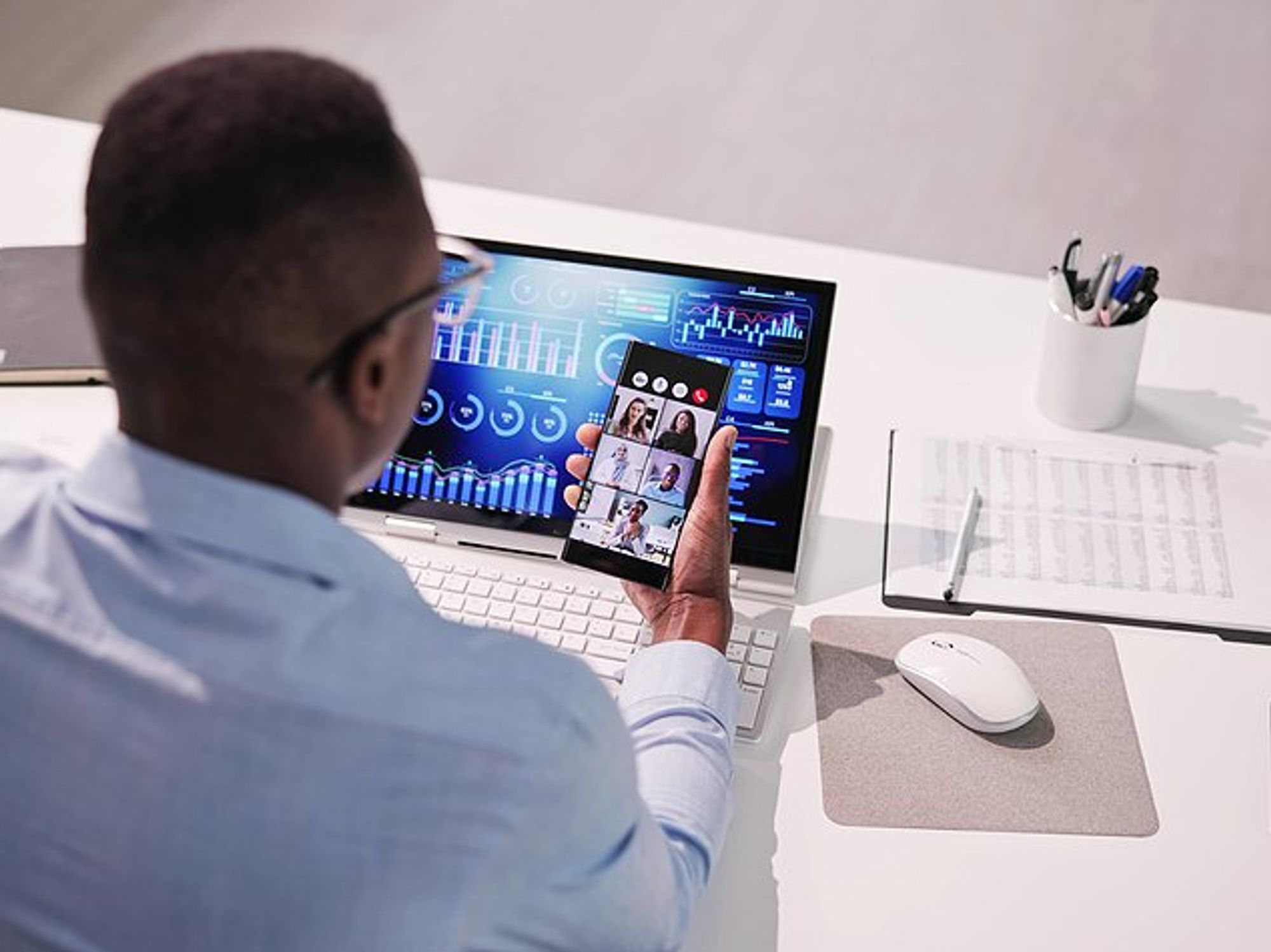Manager looks at KPI dashboard while on a video call with his coworkers
