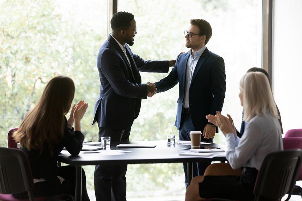 Manager shakes hands with and congratulates an employee