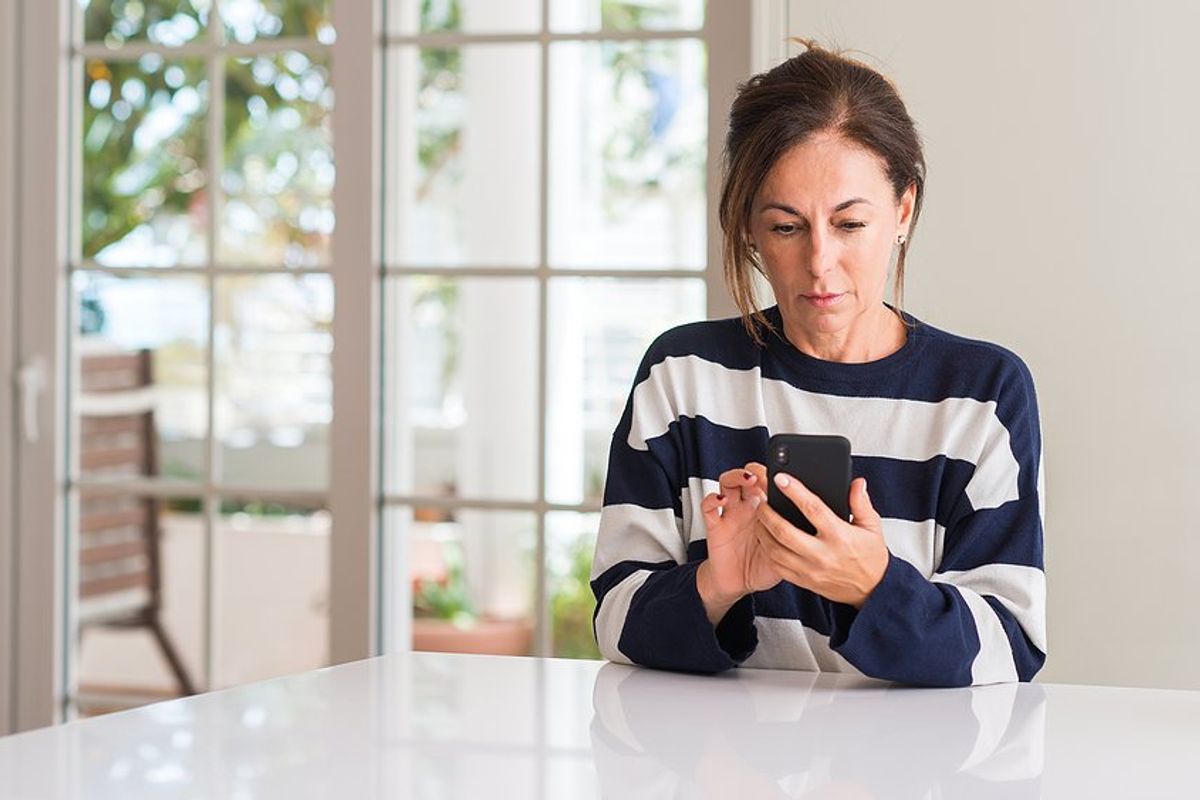 Middle aged woman on phone thinks about going back to work at 50