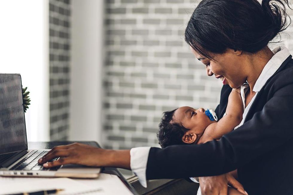 Mom holds her baby while working from home