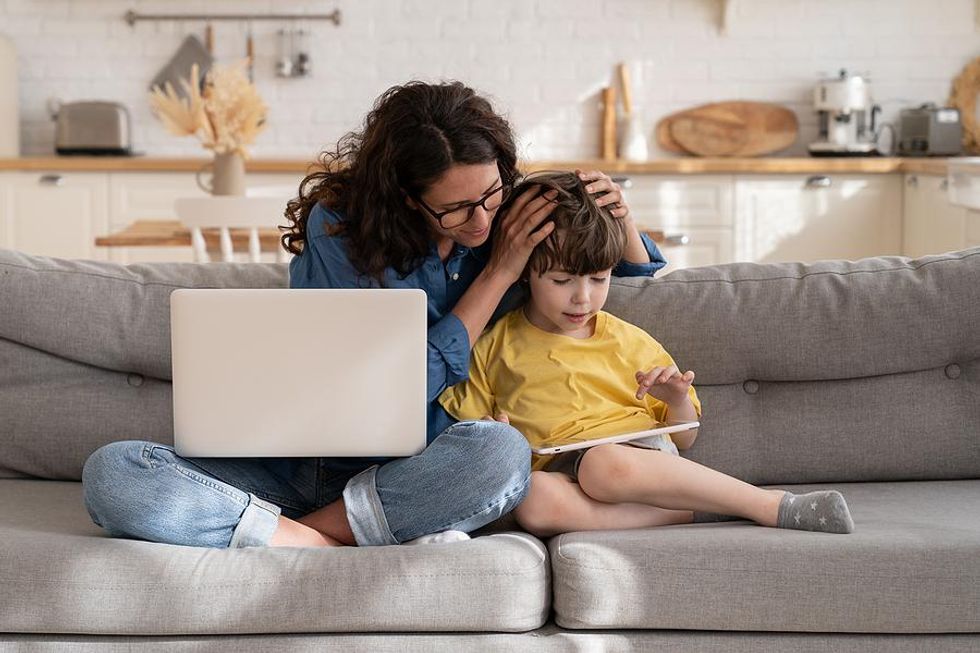 Mom sits on the couch with her son while working from home