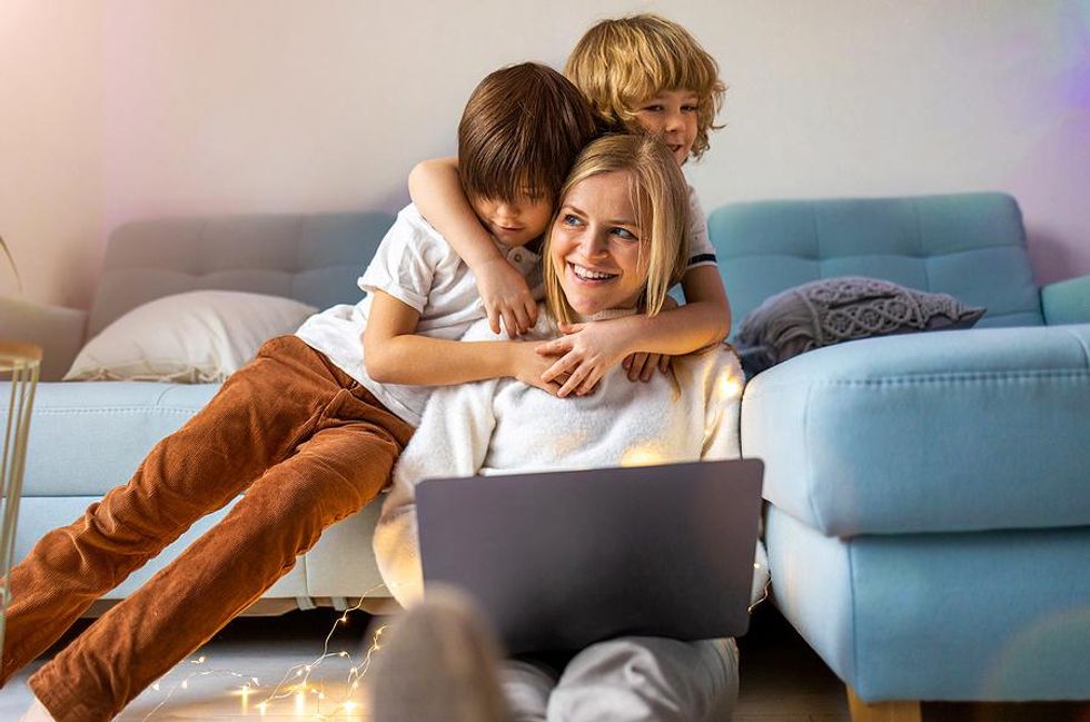 Mother receives hugs from her kids while working