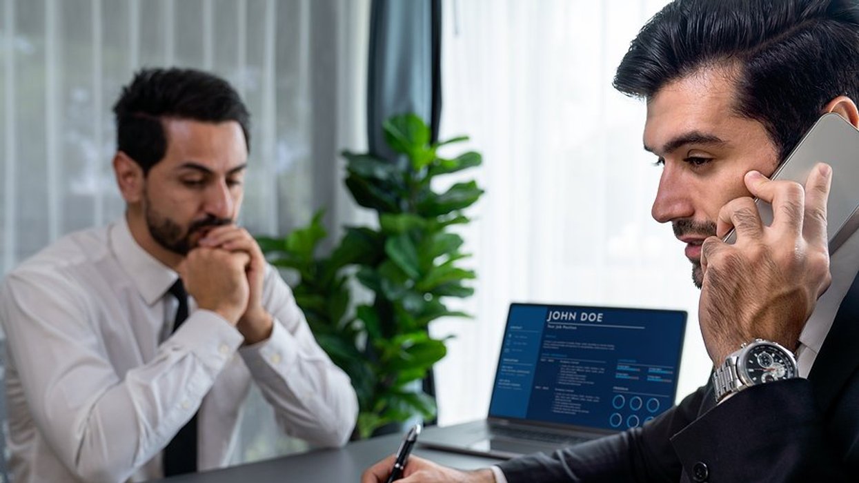 Nervous man in interview waits while the hiring manager talks on the phone