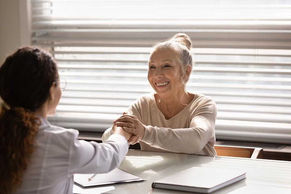 Old woman shakes hands and thanks someone at work