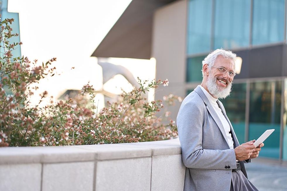 Older leader/executive smiles while holding a tablet