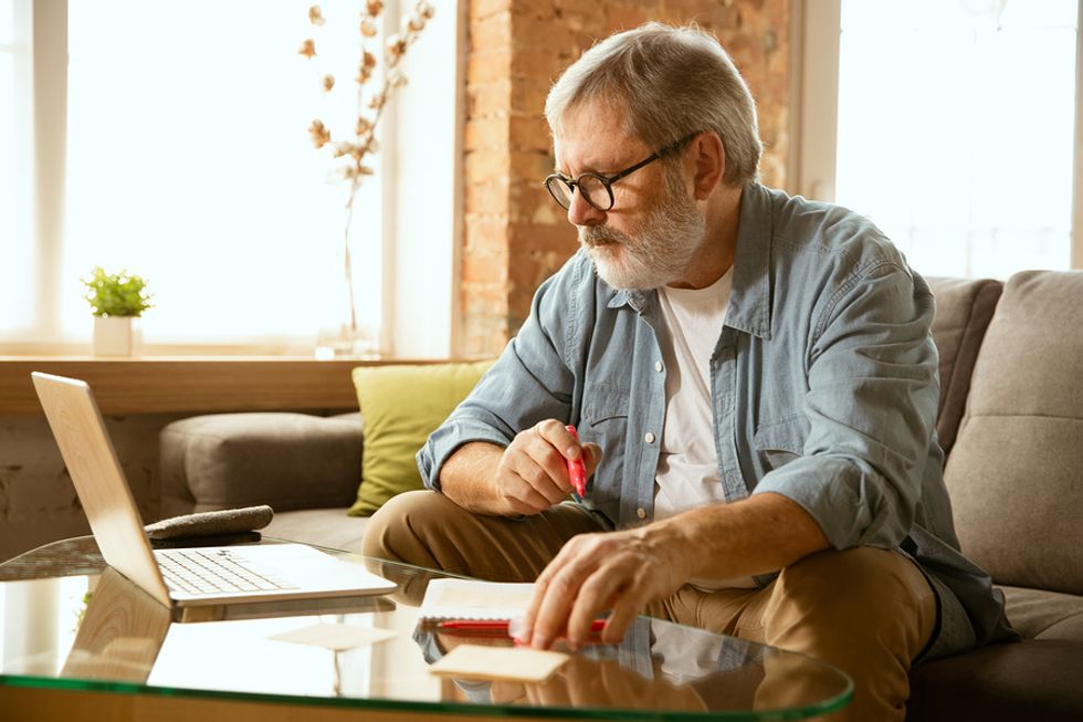 Elderly man using laptop working at home