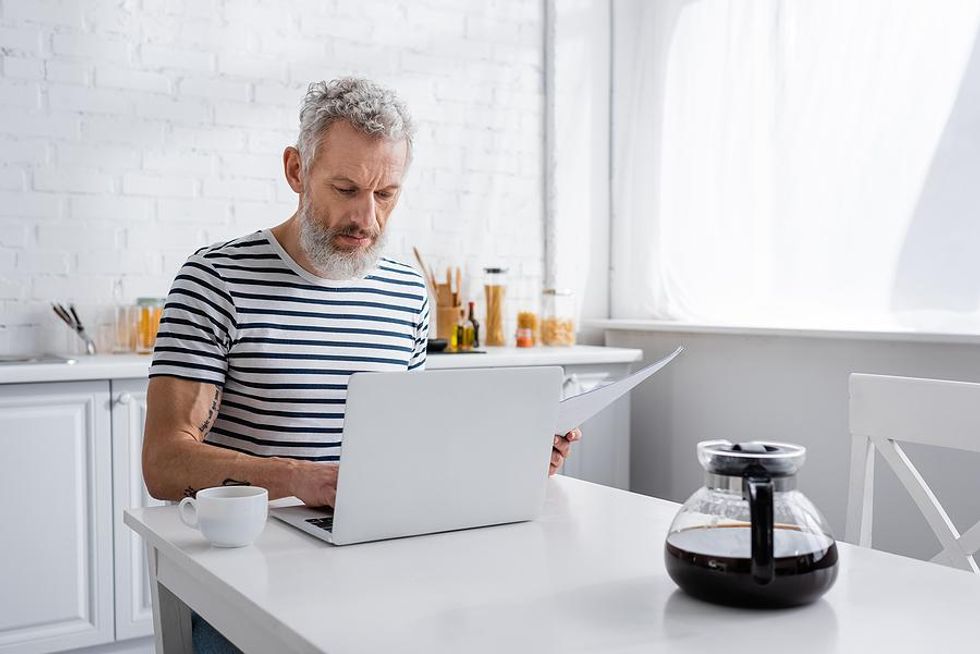 Older man on laptop writes his resume