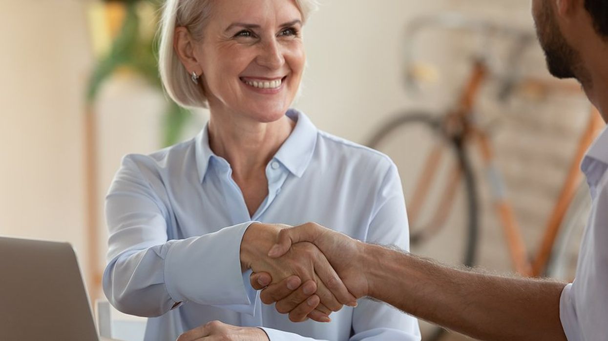 Older over 50 job seeker shakes hands with the hiring manager during a job interview