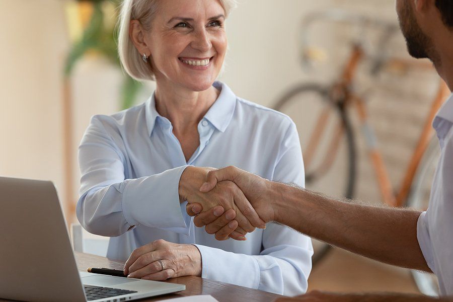 Older over 50 job seeker shakes hands with the hiring manager during a job interview