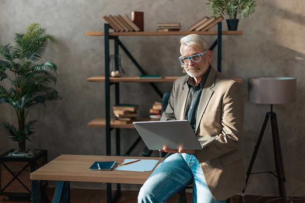 Older professional man on laptop offers value to his professional network