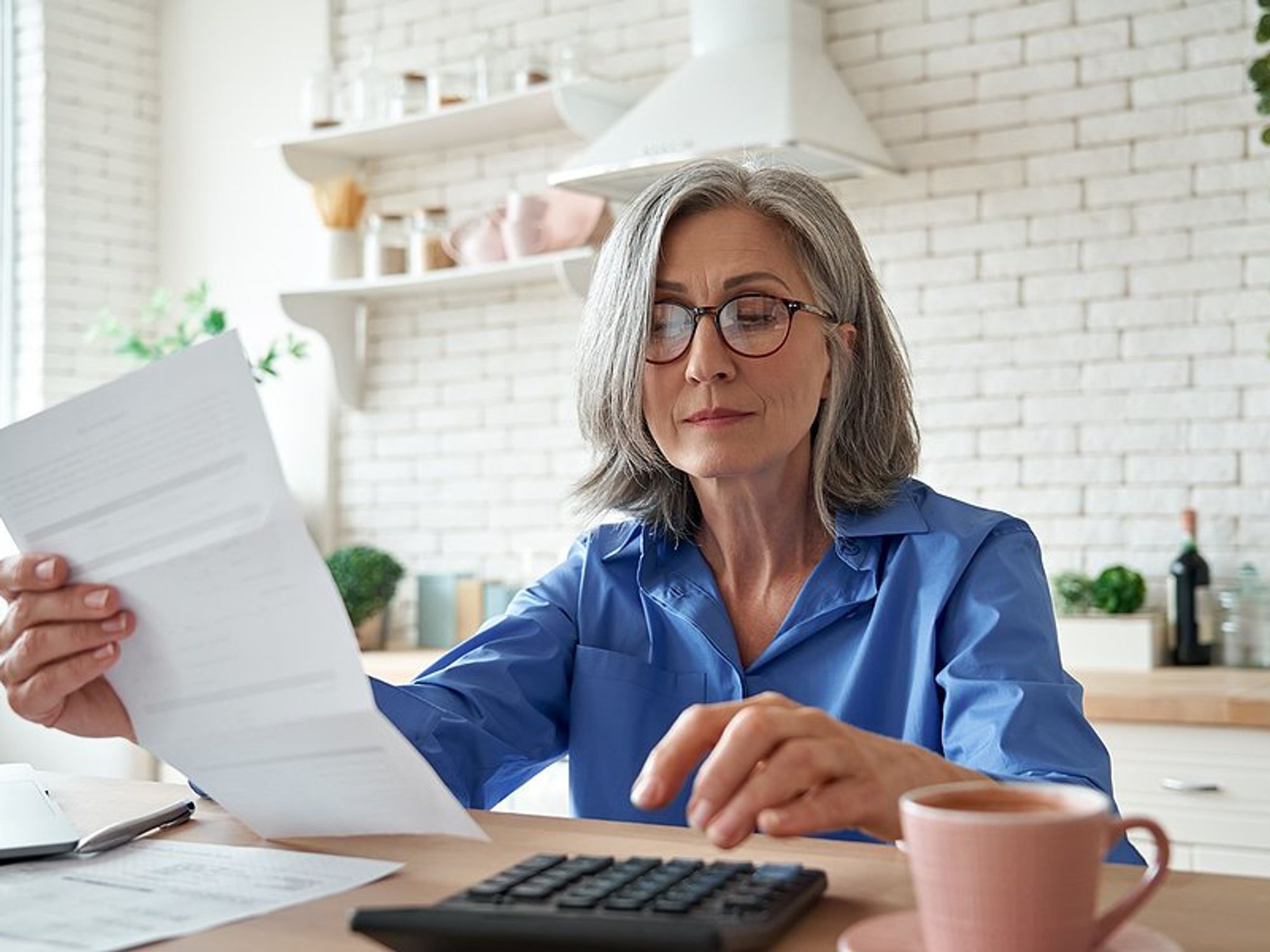 Older professional woman calculating her income after escaping the one-job trap