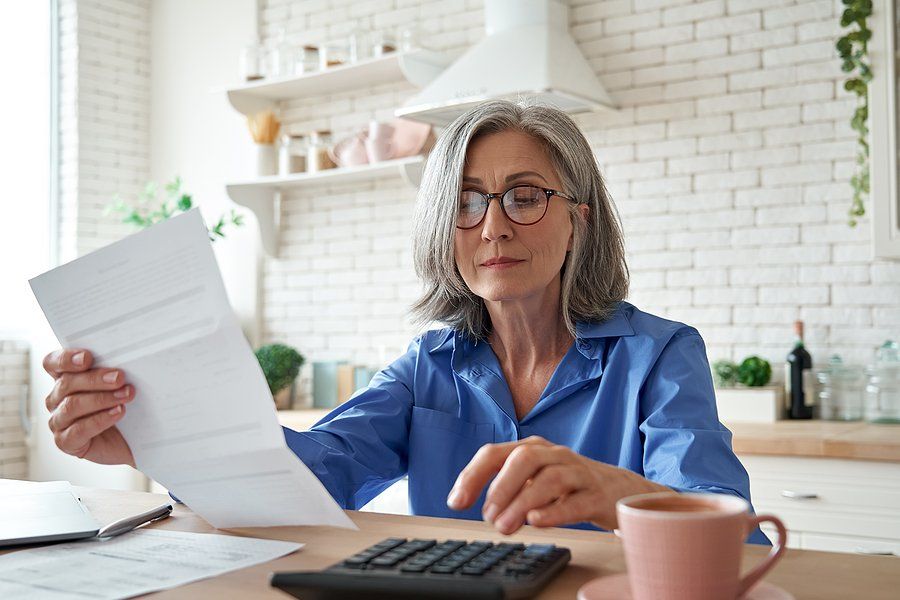 Older professional woman calculating her income after escaping the one-job trap