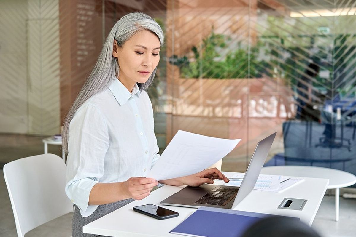 Older professional woman on laptop reads her resume to make sure it doesn't make her look old