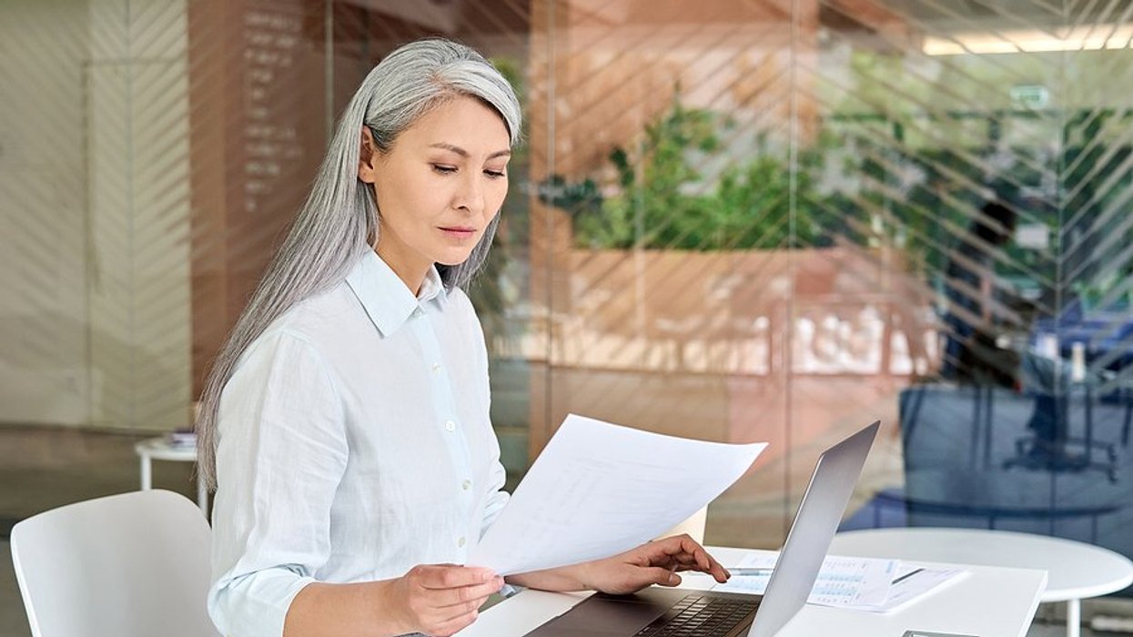 Older professional woman on laptop reads her resume to make sure it doesn't make her look old
