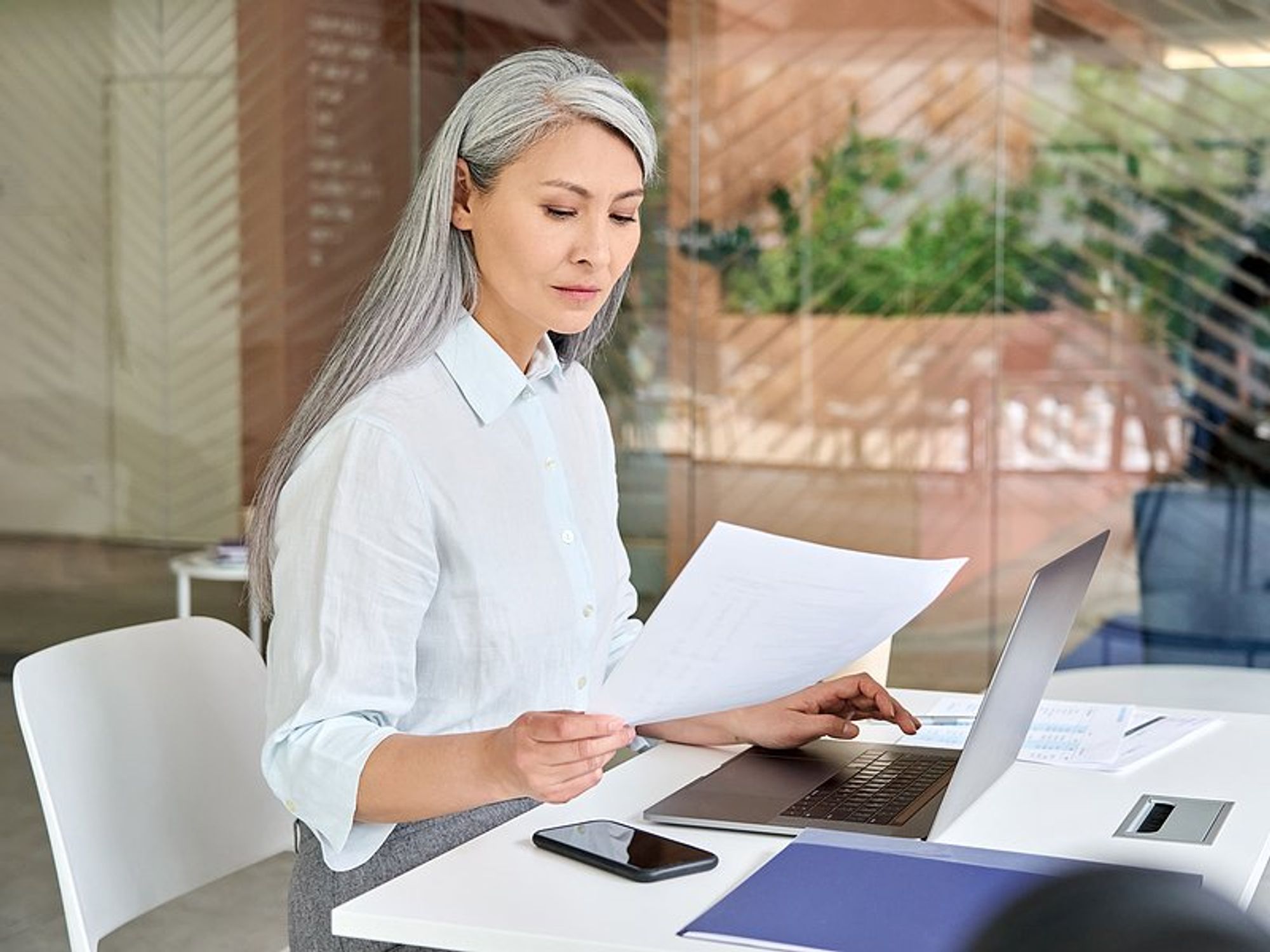 Older professional woman on laptop reads her resume to make sure it doesn't make her look old