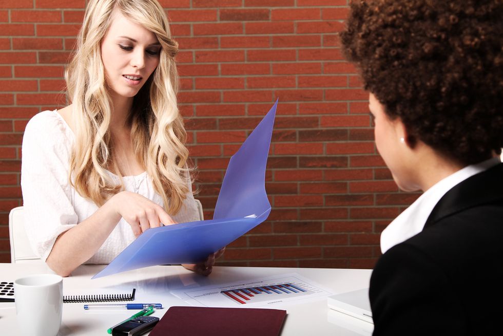 One colleague helps another during a mock interview.