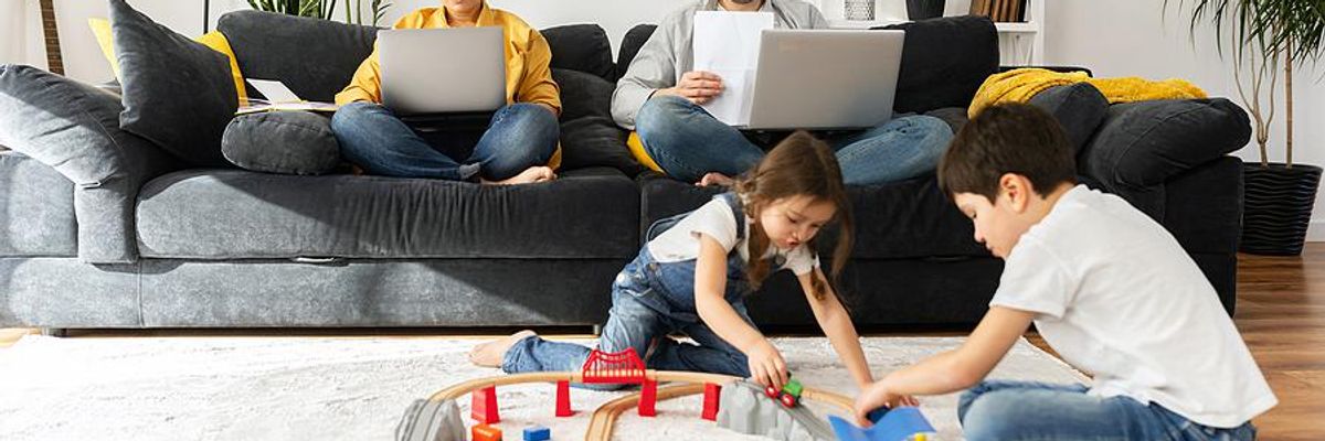 Parents work on their laptops while their children play