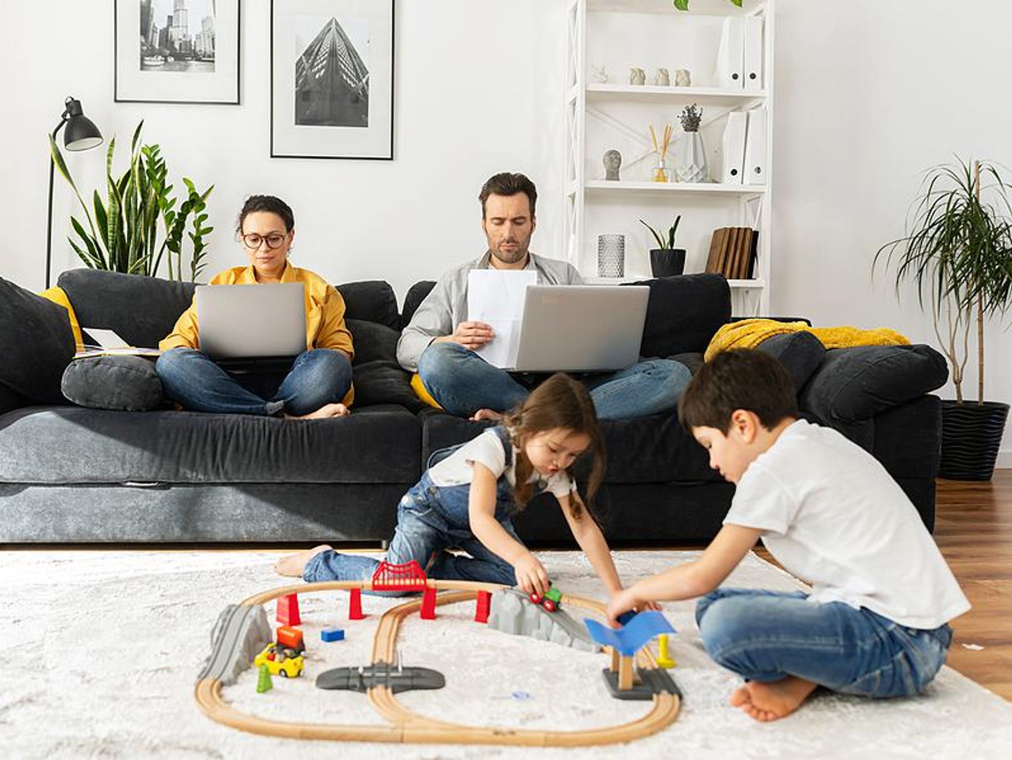 Parents work on their laptops while their children play
