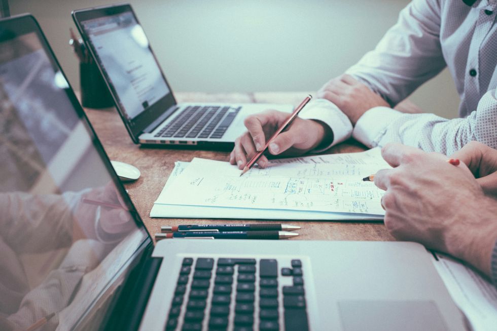 Person holding pencil near laptop computer during a project management meeting