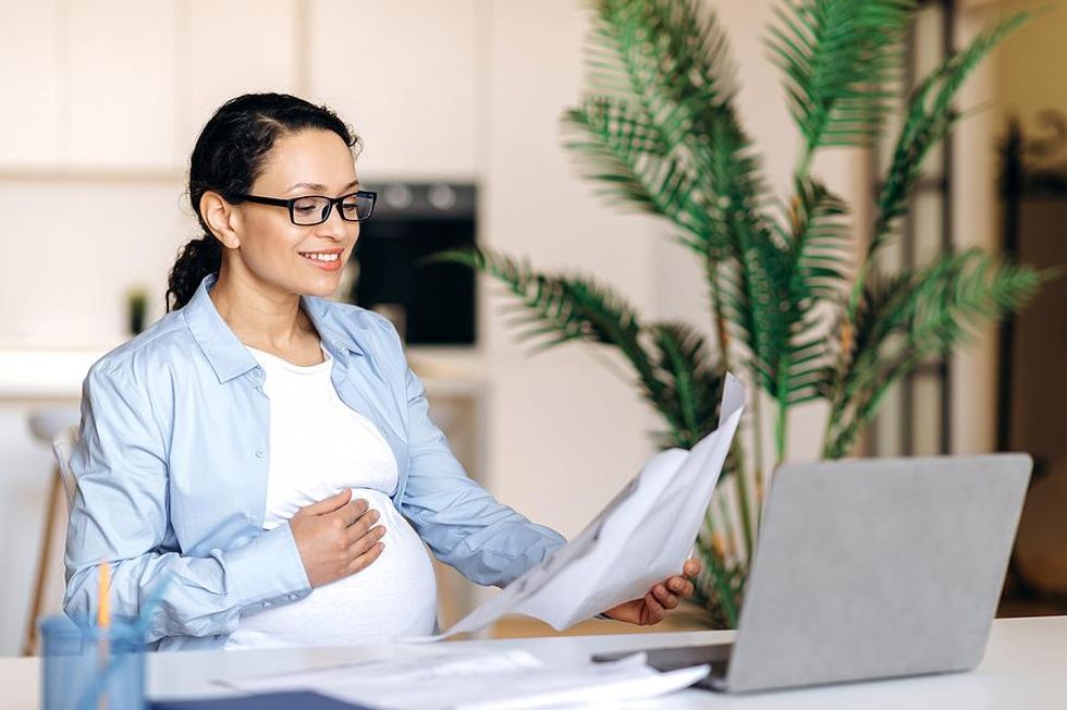 Pregnant woman sits at a desk