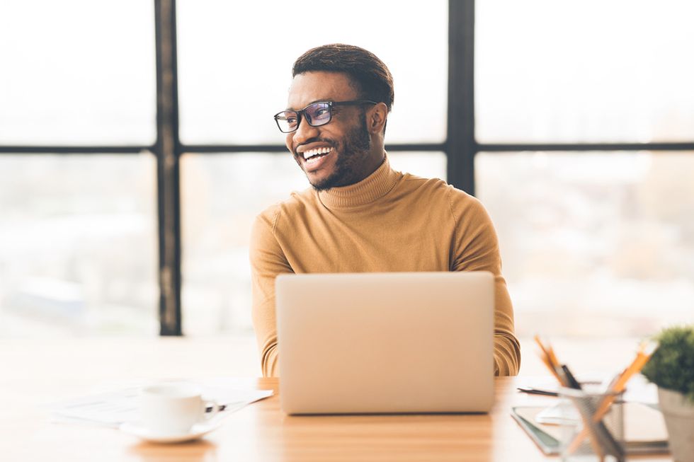 Professional man on laptop smiles while working from home