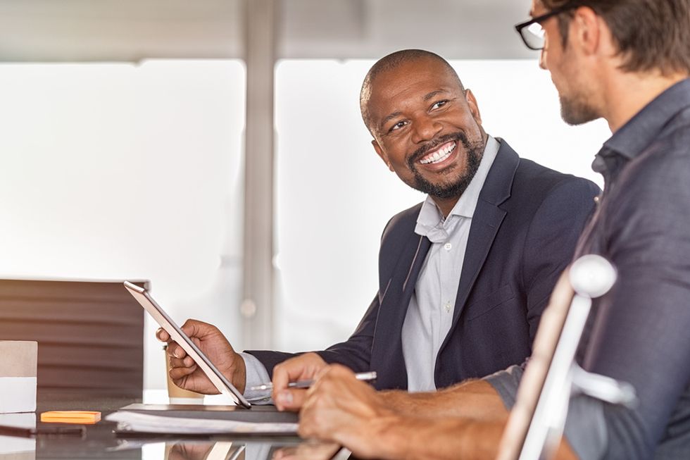 Professional man smiles while talking to a coworker