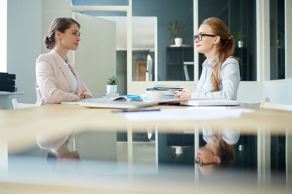 Professional woman practices her answer to the interview question, "Tell me about a time you went above and beyond?" during a job interview