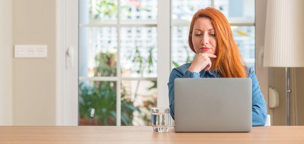 Professional woman sitting at her home laptop, wondering if the career she wants to pursue is realistic.